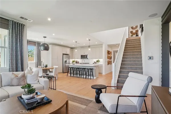 a living room with furniture and a dining table with wooden floor