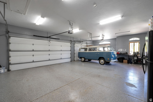 513 Southfork Drive Draper, UT 84020 - Photo 70 of 70 Spacious garage featuring a durable epoxy floor coating, two overhead garage doors, ample overhead lighting, and an arched window