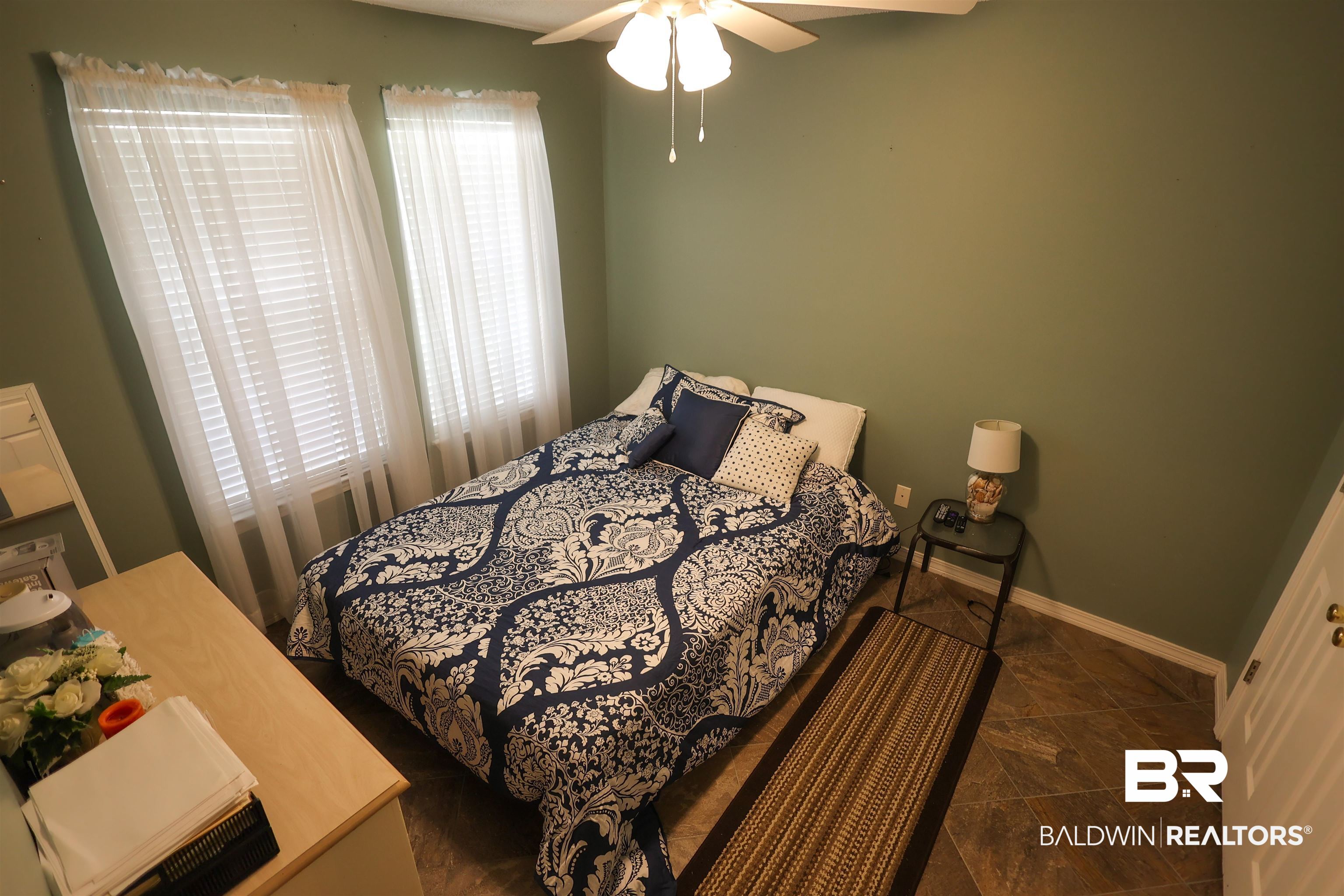 7790 Audubon Drive Foley, AL 36535 - Photo 26 of 39 Room featuring two windows with blinds, a ceiling fan with integrated lighting, and wood-finish flooring
