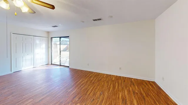 a view of an empty room with wooden floor and window