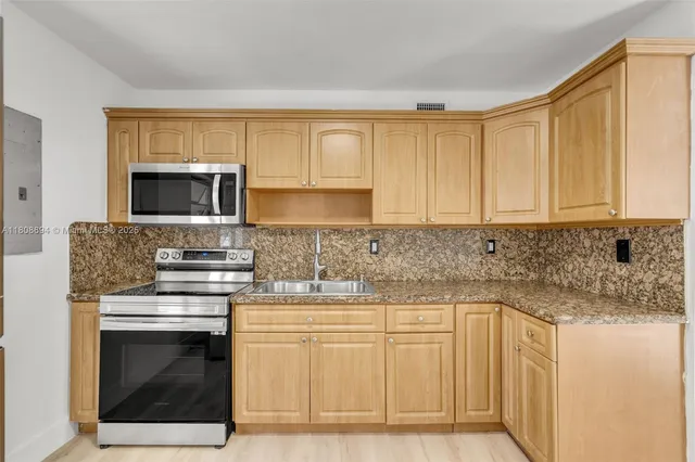 a kitchen with granite countertop white cabinets and stainless steel appliances