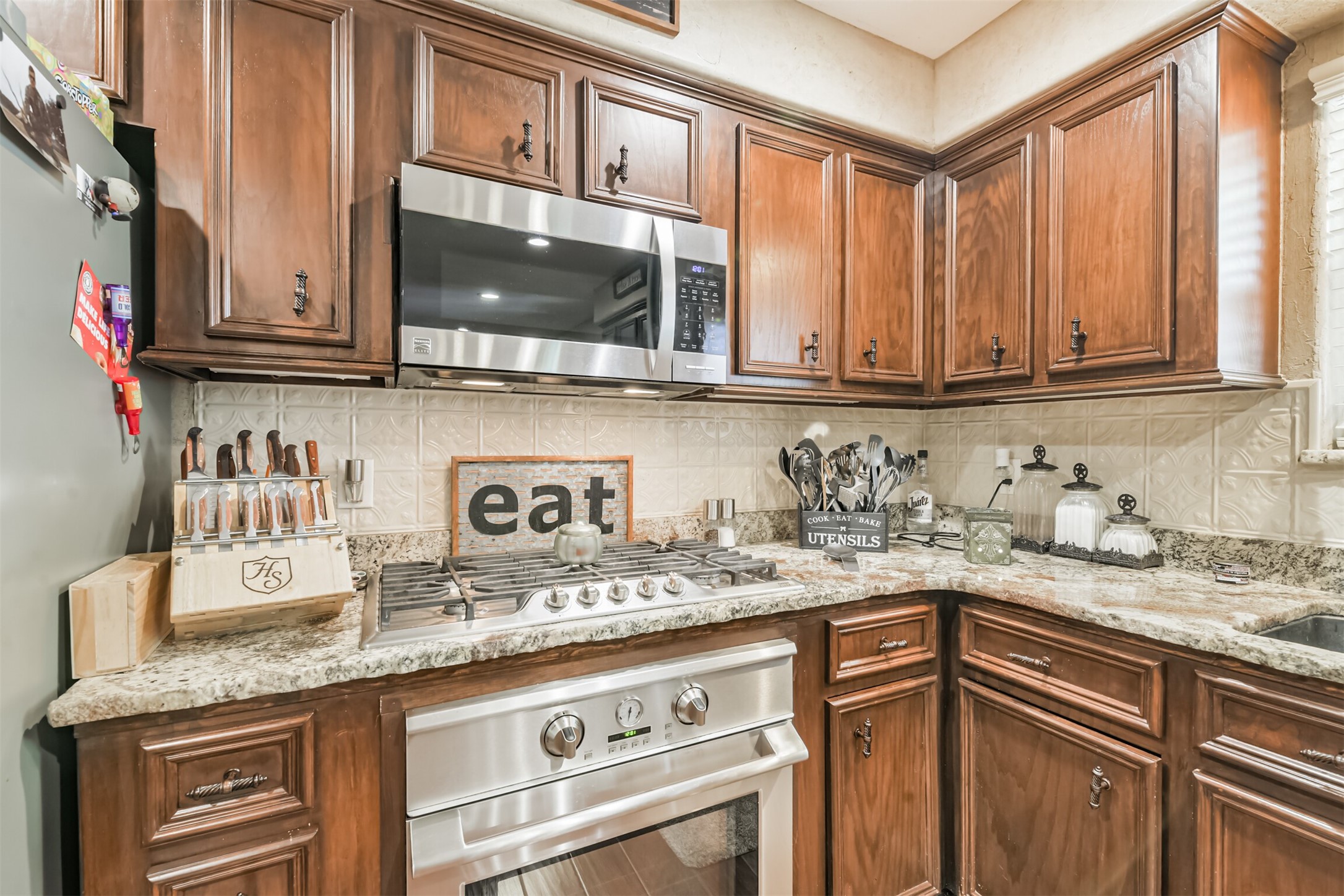 307 West Hufsmith Road Tomball, TX 77375 - Photo 19 of 44 Charming kitchen with rich wooden cabinetry, granite countertops, and stainless steel appliances, perfect for culinary enthusiasts.