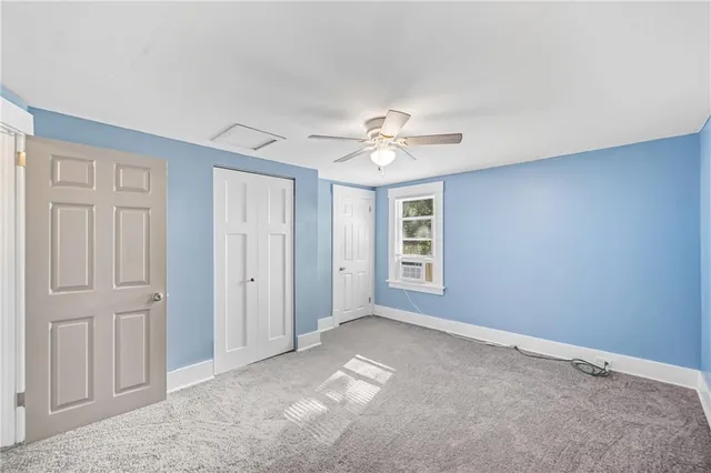 an empty room with a window and a ceiling fan