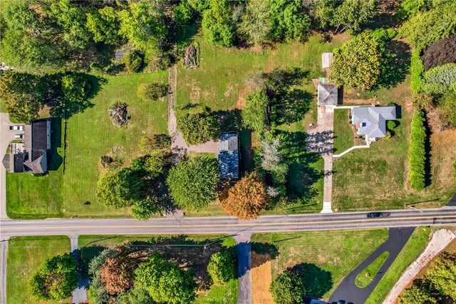 an aerial view of residential houses with outdoor space and trees