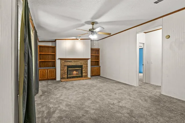 an empty room with windows fireplace and fan