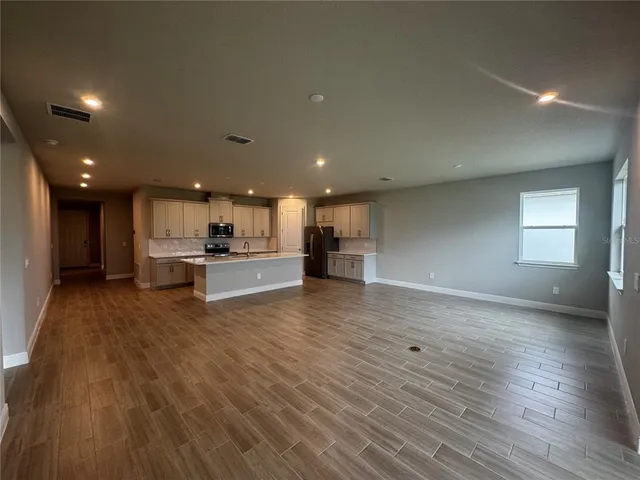 a view of kitchen with kitchen island a sink wooden floor and a refrigerator
