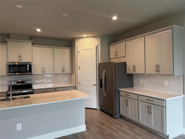 a kitchen with granite countertop a refrigerator and a stove top oven
