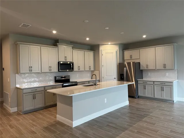 a kitchen with a sink a counter top space stainless steel appliances and cabinets