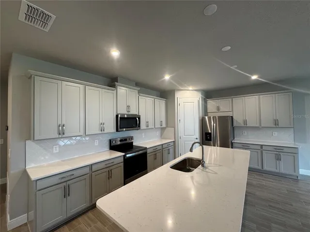 a kitchen with kitchen island a white counter top space cabinets and stainless steel appliances