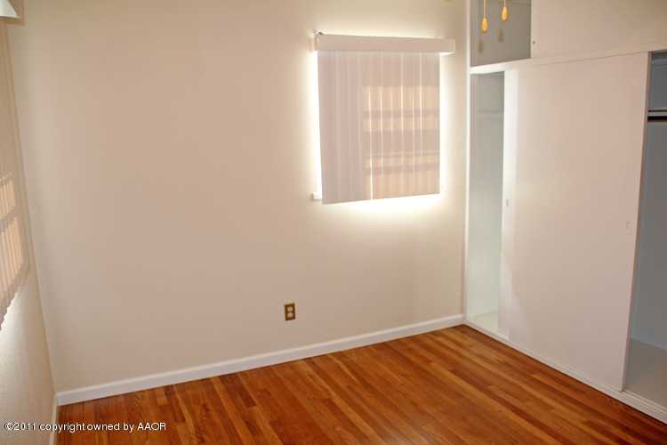 5127 Crockett Street Amarillo, TX 79110 - Photo 11 of 25 a view of an empty room with wooden floor and a window