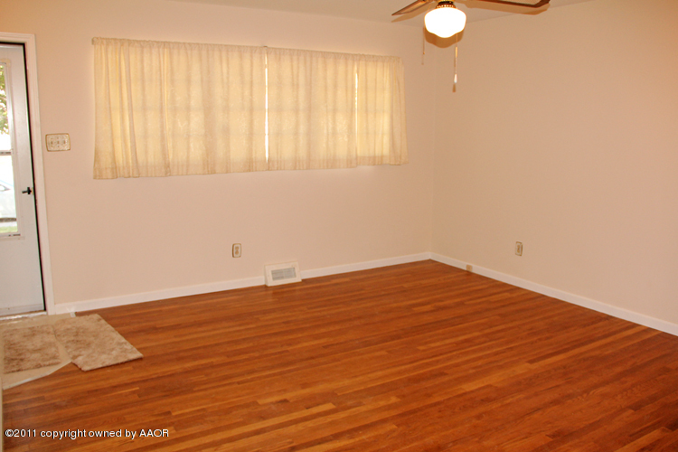 5127 Crockett Street Amarillo, TX 79110 - Photo 4 of 25 a view of an empty room with wooden floor and a window