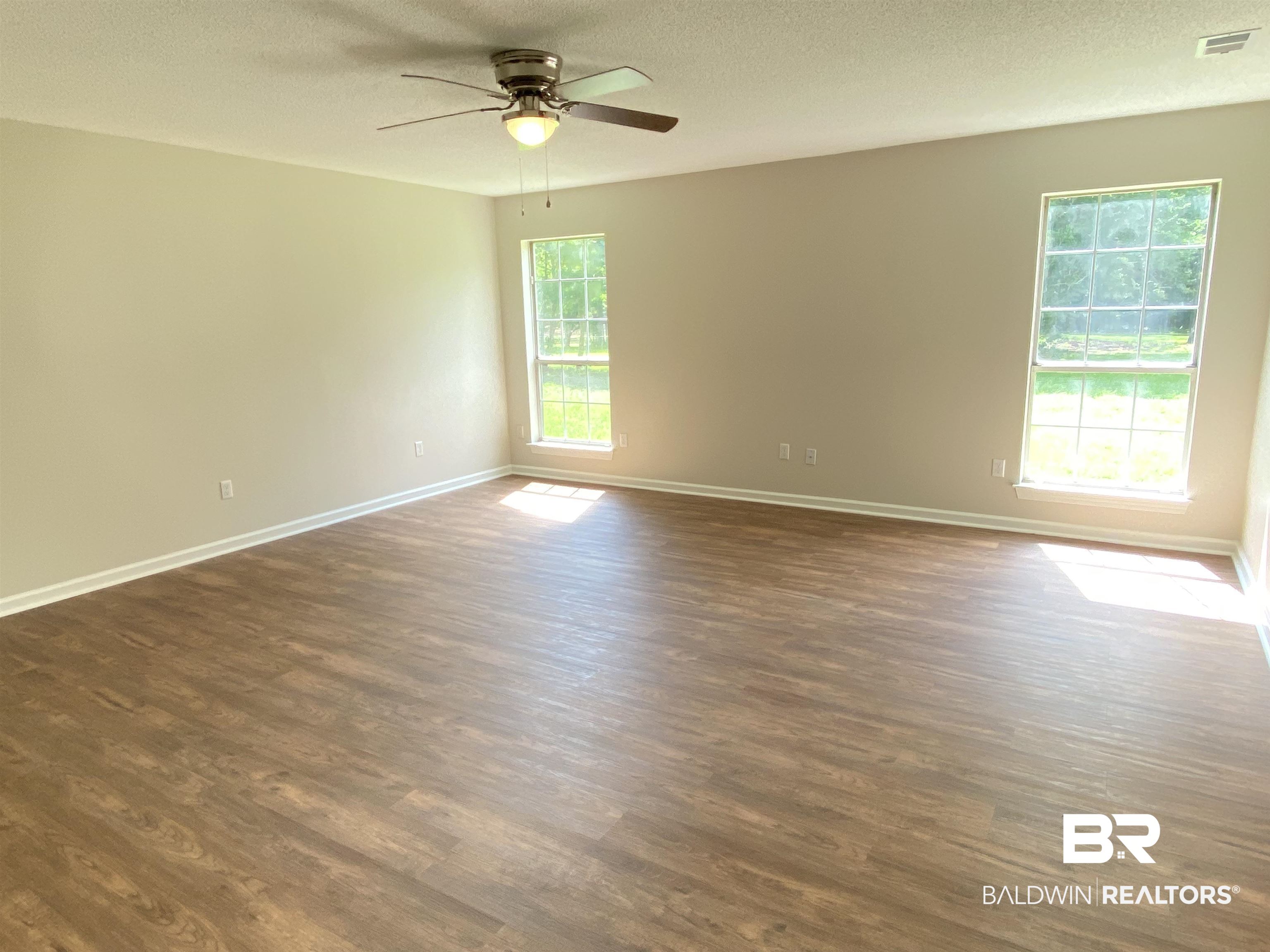 12150 Lee Bishop Road Irvington, AL 36544 - Photo 14 of 26 Spare room featuring visible vents, a ceiling fan, baseboards, and dark wood-type flooring