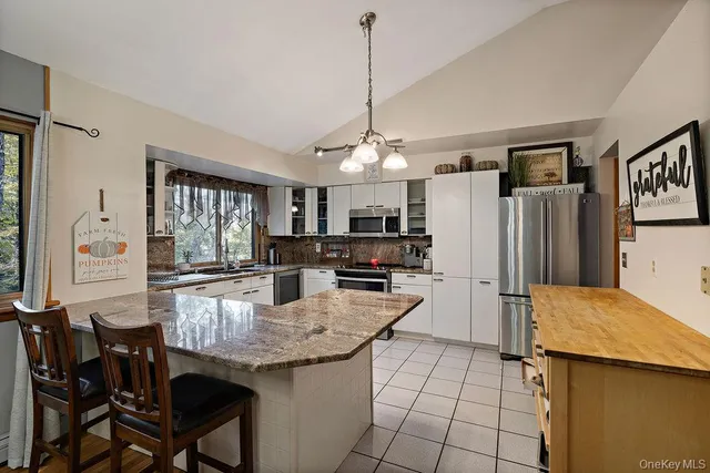 a kitchen with stainless steel appliances granite countertop a stove top oven a sink dishwasher a dining table and chairs with wooden floor