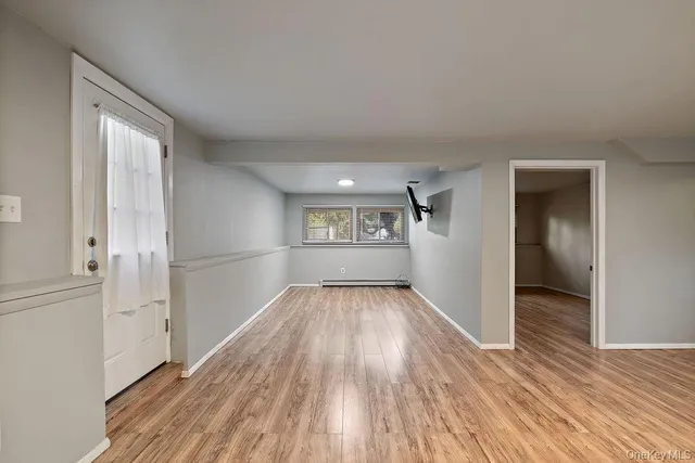an empty room with wooden floor a fireplace and windows