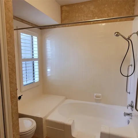 a bathroom with a granite countertop sink a toilet and shower