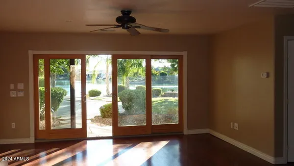 a view of empty room with wooden floor and fan