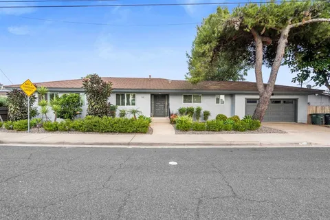 a front view of a house with a yard and potted plants