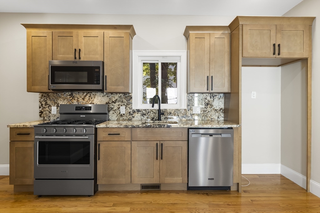 31 Woodale Avenue, Unit 1 Boston, MA 02126 - Photo 4 of 22 a kitchen with stainless steel appliances granite countertop a stove a sink and a microwave