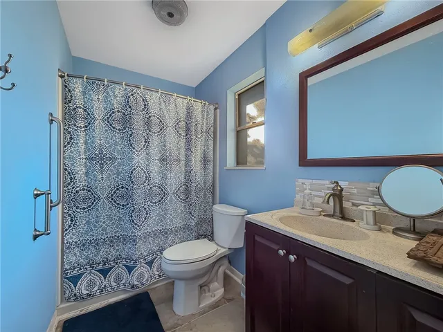 a bathroom with a toilet sink a mirror a vanity and shower