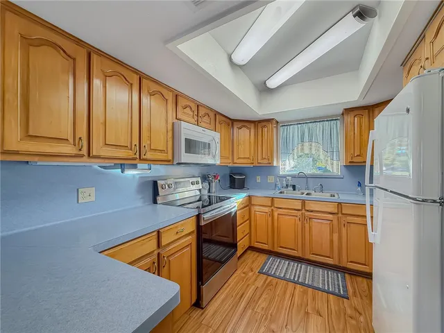 a kitchen with stainless steel appliances granite countertop a sink a stove a refrigerator with grey cabinets and wooden floor