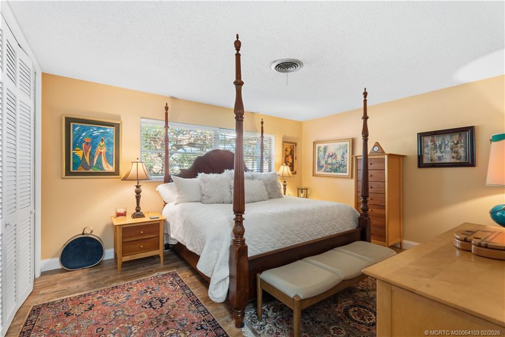 900 Northwest 11th Terrace Stuart, FL 34994 - Photo 23 of 35 a bedroom with a bed a desk and chair with the wooden floor