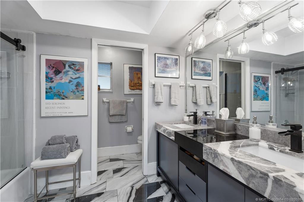 900 Northwest 11th Terrace Stuart, FL 34994 - Photo 10 of 35 a bathroom with a granite countertop sink a toilet a shower and a mirror