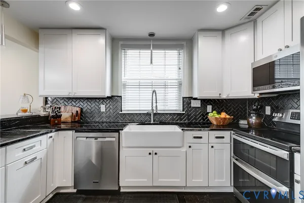 a kitchen with granite countertop white cabinets and black stainless steel appliances
