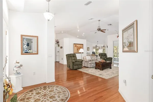 a living room with kitchen island a stove a refrigerator and a wooden floor