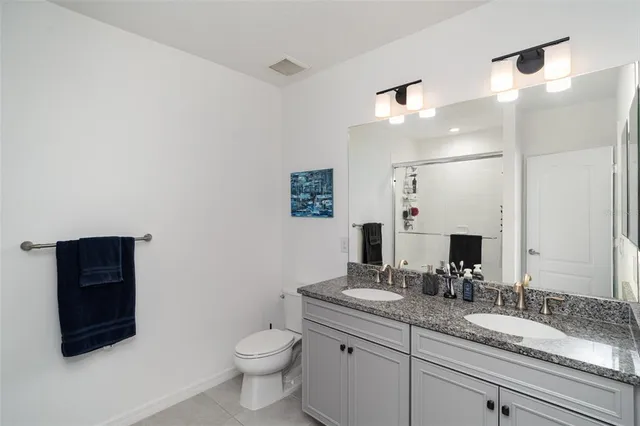 a bathroom with a granite countertop toilet sink and mirror