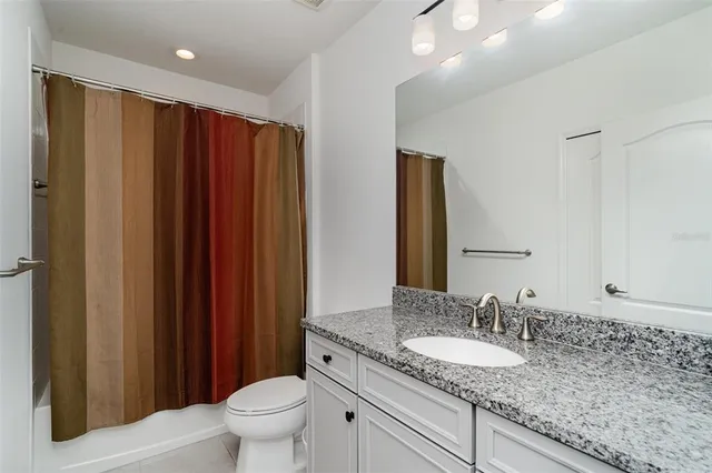 a bathroom with a granite countertop sink toilet and mirror