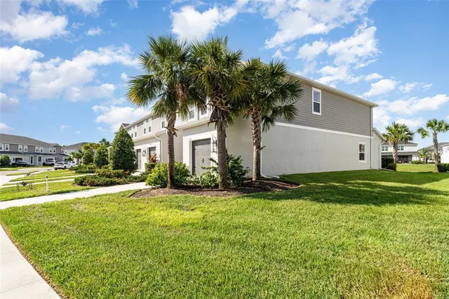 a view of a white house with a big yard and palm trees