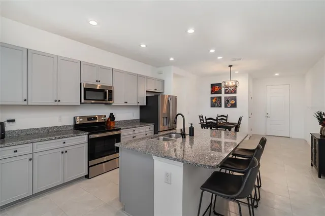 a kitchen with kitchen island granite countertop a sink a counter space appliances and cabinets