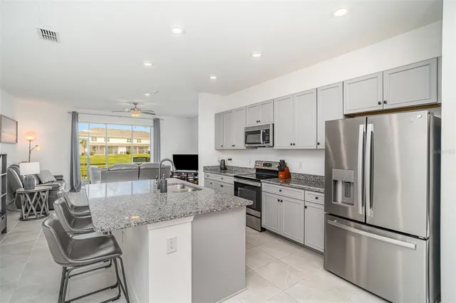 a kitchen with stainless steel appliances granite countertop a refrigerator a stove a sink a dining table and chairs