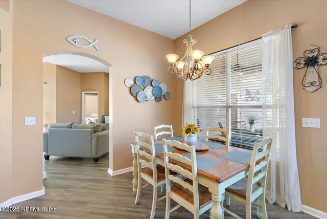 a dining room with furniture a chandelier and wooden floor