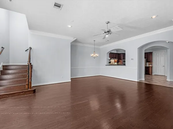 an empty room with wooden floor ceiling fan and windows