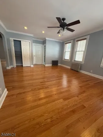a view of an empty room with window and wooden floor