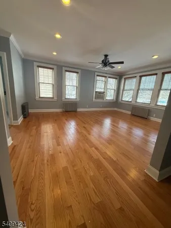 a view of empty room with wooden floor and fan