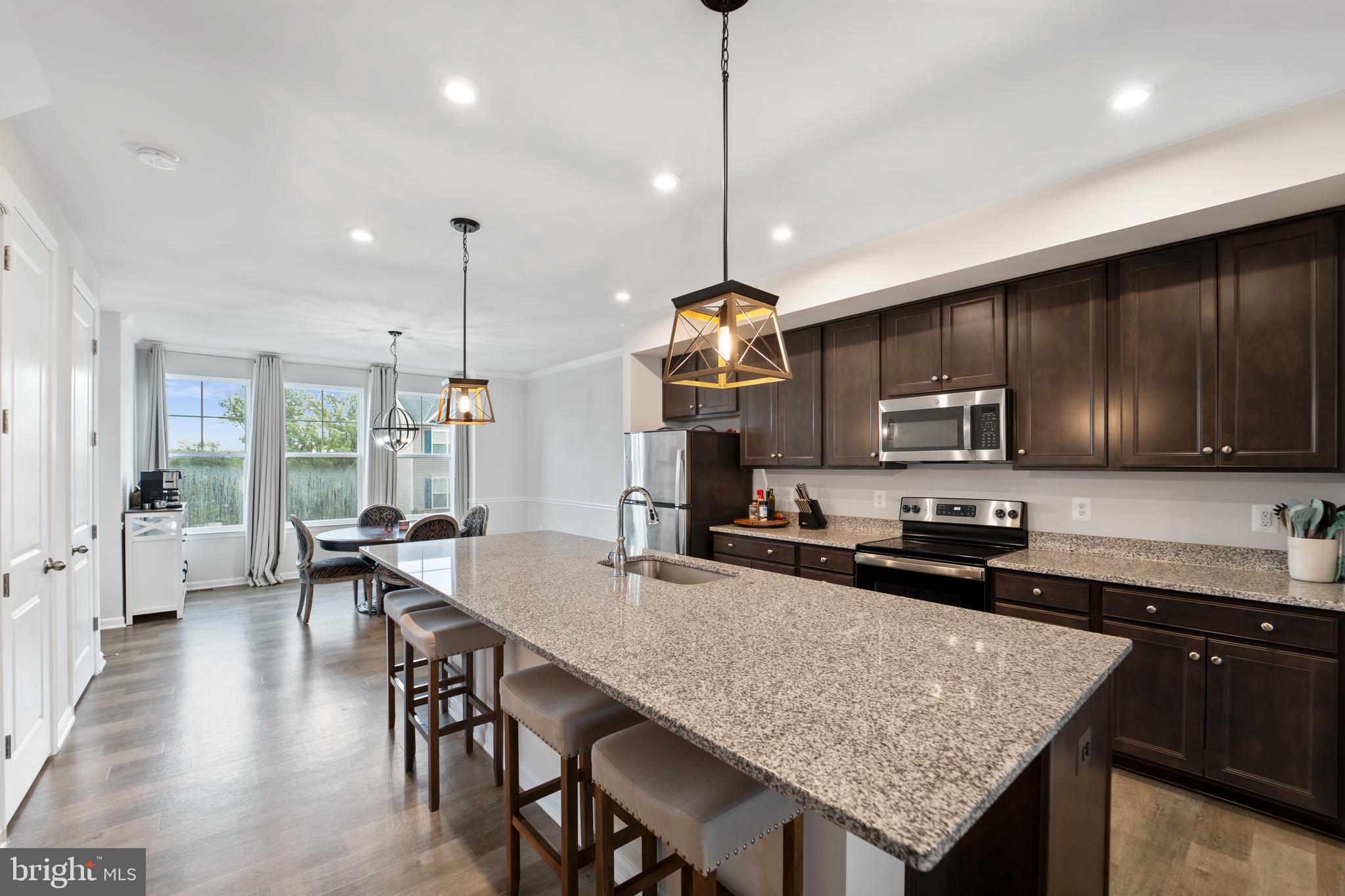 18216 Summit Pointe Drive Triangle, VA 22172 - Photo 4 of 25 a kitchen with granite countertop a stove a sink a kitchen island with chairs and wooden floor