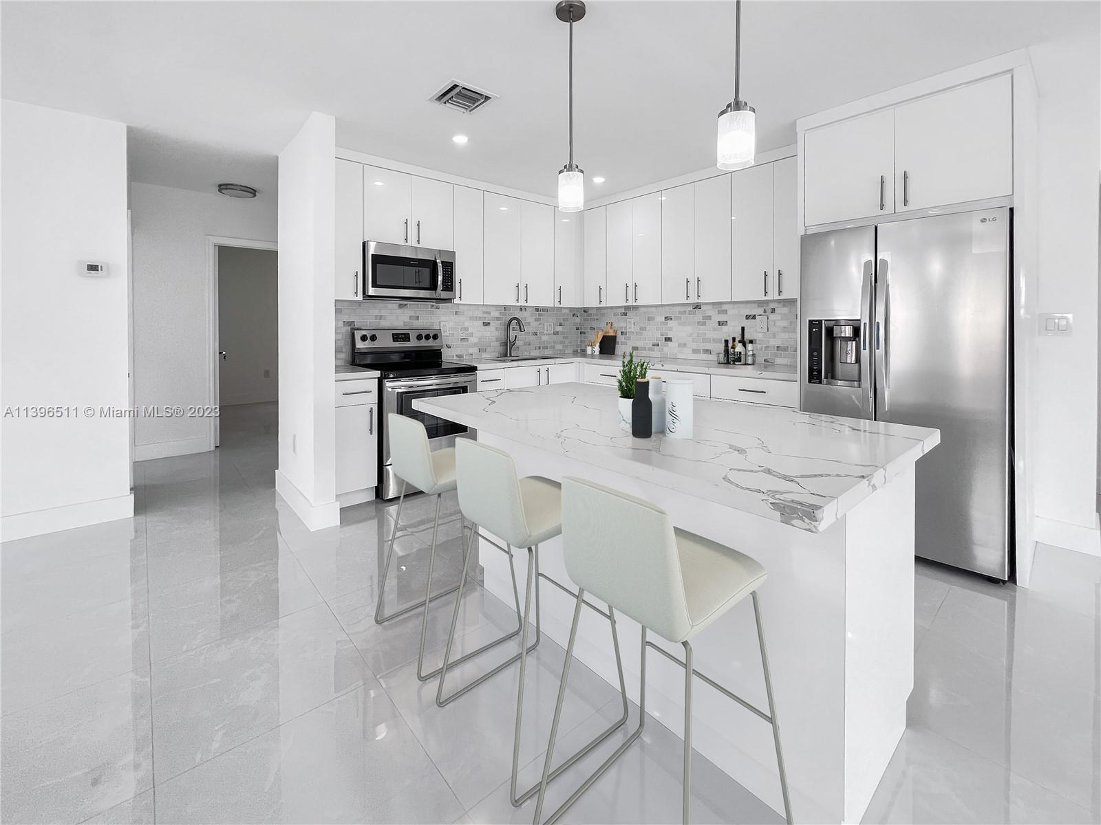 2180 Southwest 20th Street Miami, FL 33145 - Photo 5 of 31 a kitchen with stainless steel appliances granite countertop a stove a refrigerator a kitchen island a sink and a refrigerator with wooden floor