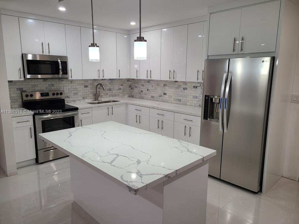 2180 Southwest 20th Street Miami, FL 33145 - Photo 6 of 31 a kitchen with stainless steel appliances a microwave a sink a stove a refrigerator and island