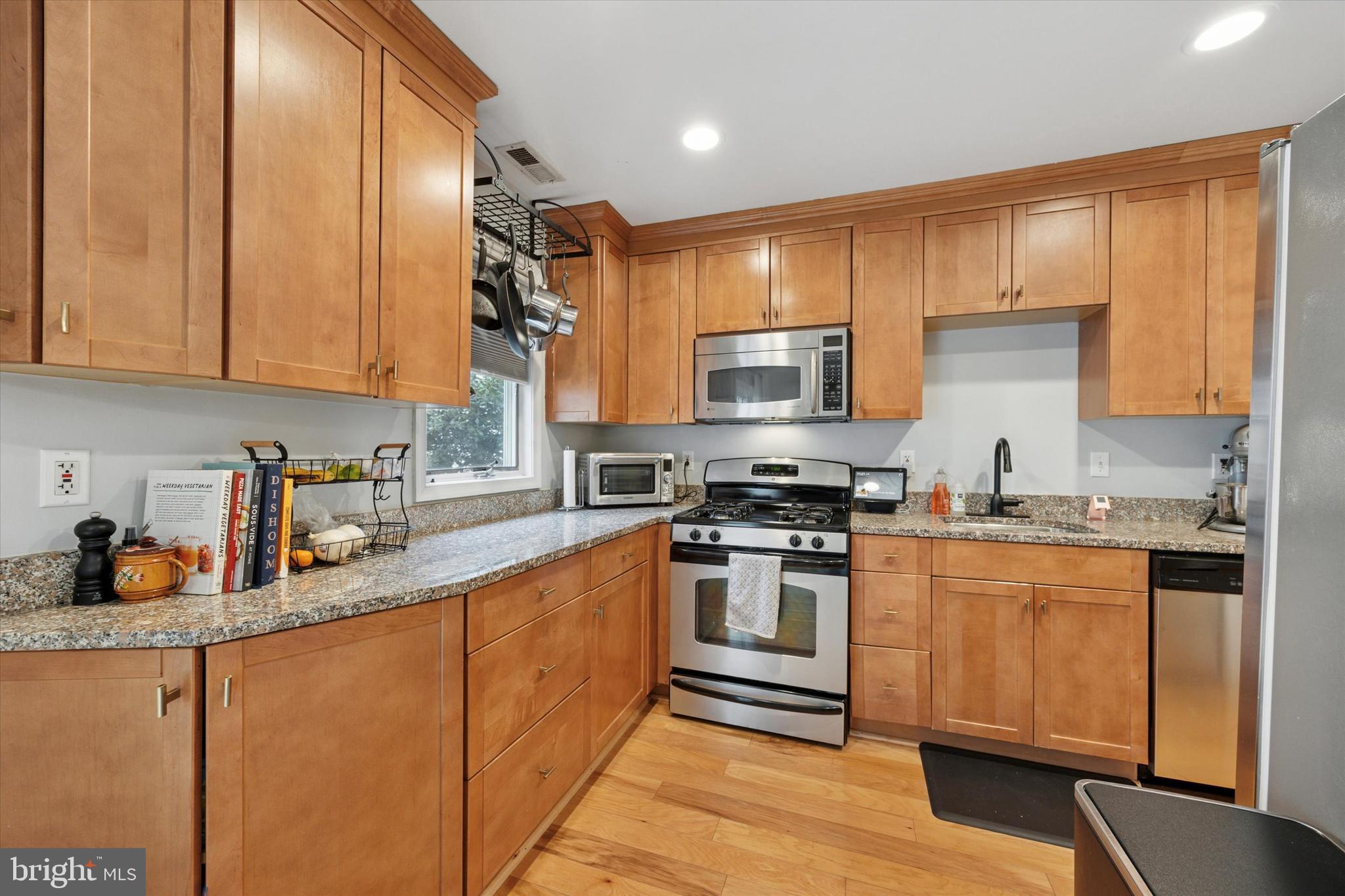 814 South Sheridan Street, Unit 2E Philadelphia, PA 19147 - Photo 8 of 24 a kitchen with stainless steel appliances granite countertop a stove a sink dishwasher and a refrigerator with wooden floor