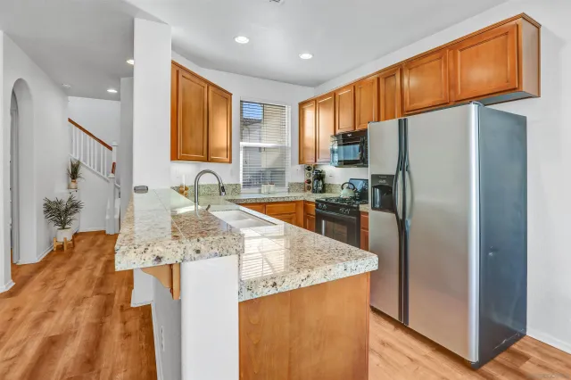a kitchen with stainless steel appliances granite countertop a refrigerator a sink and a stove
