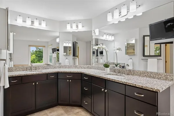 a bathroom with a granite countertop sink a mirror and cabinets