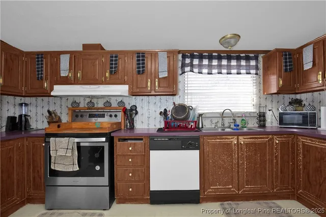 a kitchen with stainless steel appliances granite countertop a stove a sink and a microwave