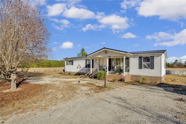 a front view of a house with a yard covered with snow and trees