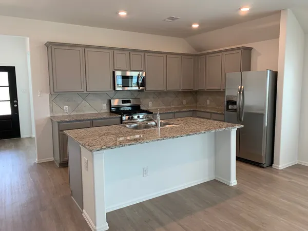 a kitchen with kitchen island granite countertop a sink a counter top space stainless steel appliances and cabinets