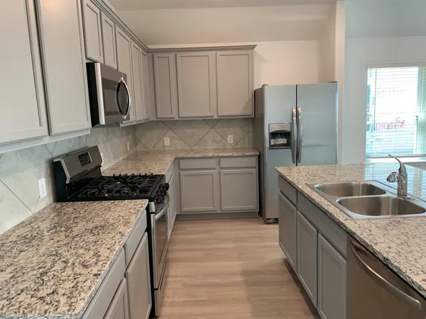 a kitchen with stainless steel appliances granite countertop a sink stove and refrigerator