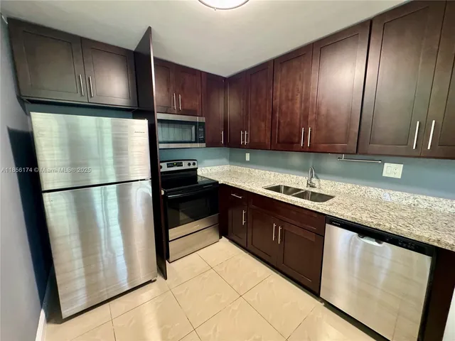 a kitchen with granite countertop wooden cabinets a refrigerator and a sink