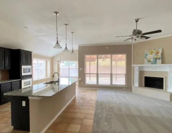 a large kitchen with granite countertop a sink a counter top space appliances and cabinets