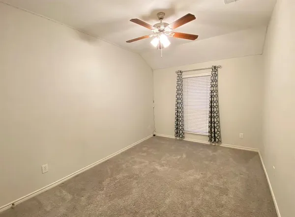 an empty room with a chandelier fan and windows